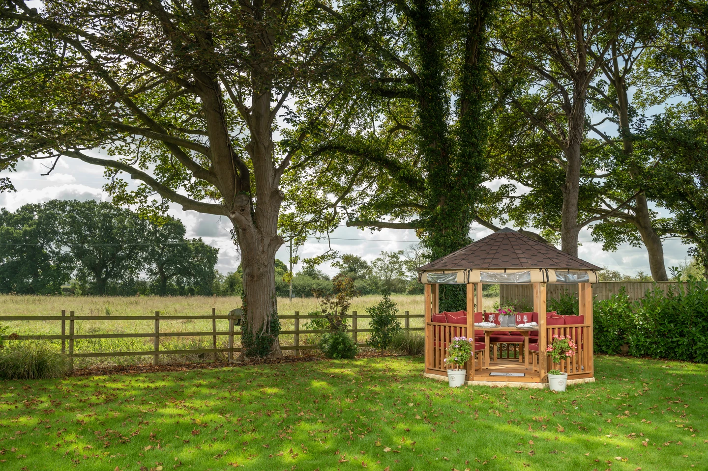 Traditional summer house beneath oak trees in countryside setting